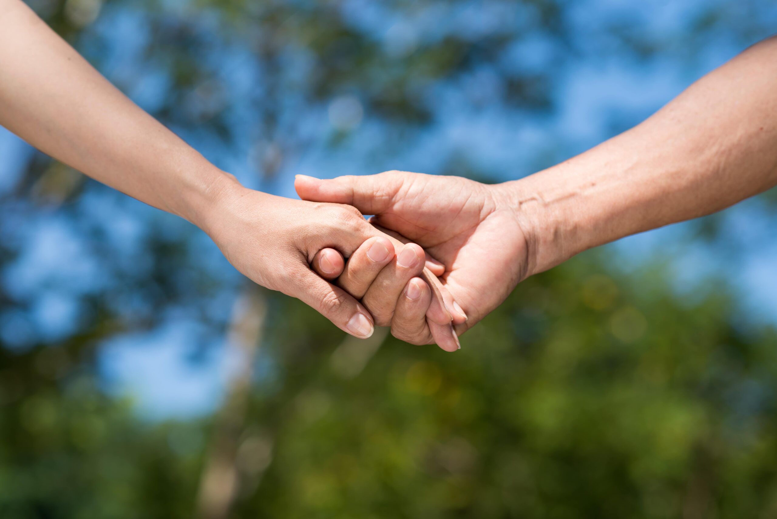 zdjęcie ilustrujące zmiany w świadczeniu wspierającym, pokazuje dwie osoby trzymające się za ręce. W tle drzewa.