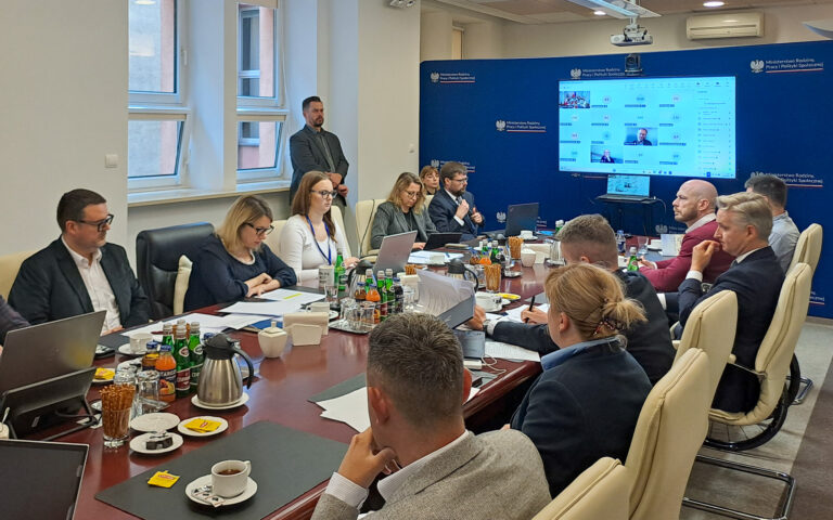 Posiedzenie Krajowej Rady Konsultacyjnej do Spraw Osób Niepełnosprawnych w siedzibie MRPiPS. Uczestnicy siedzą przy stole konferencyjnym, część osób bierze udział w spotkaniu zdalnie. Wśród uczestników są Pełnomocniczka Rządu ds. Osób Niepełnosprawnych Monika Sikora i dyrektor BON Krzysztof Czechowski.